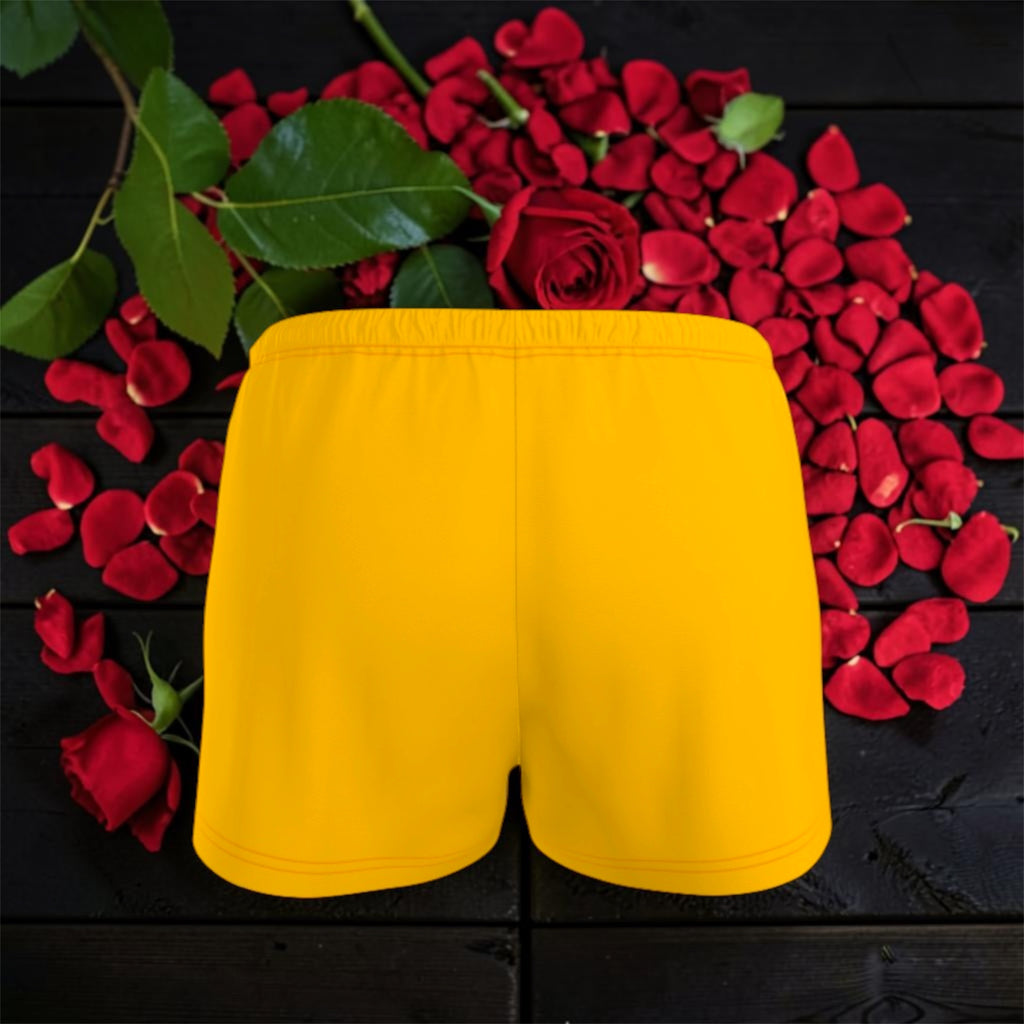 Image 3 — Back flat lay (dark backdrop, rose petals): Golden Expression Art Vol IV The Golden Ease Short — golden yellow organic cotton shorts back view, elastic waistband, surrounded by red rose petals — Stay Golden Edit
