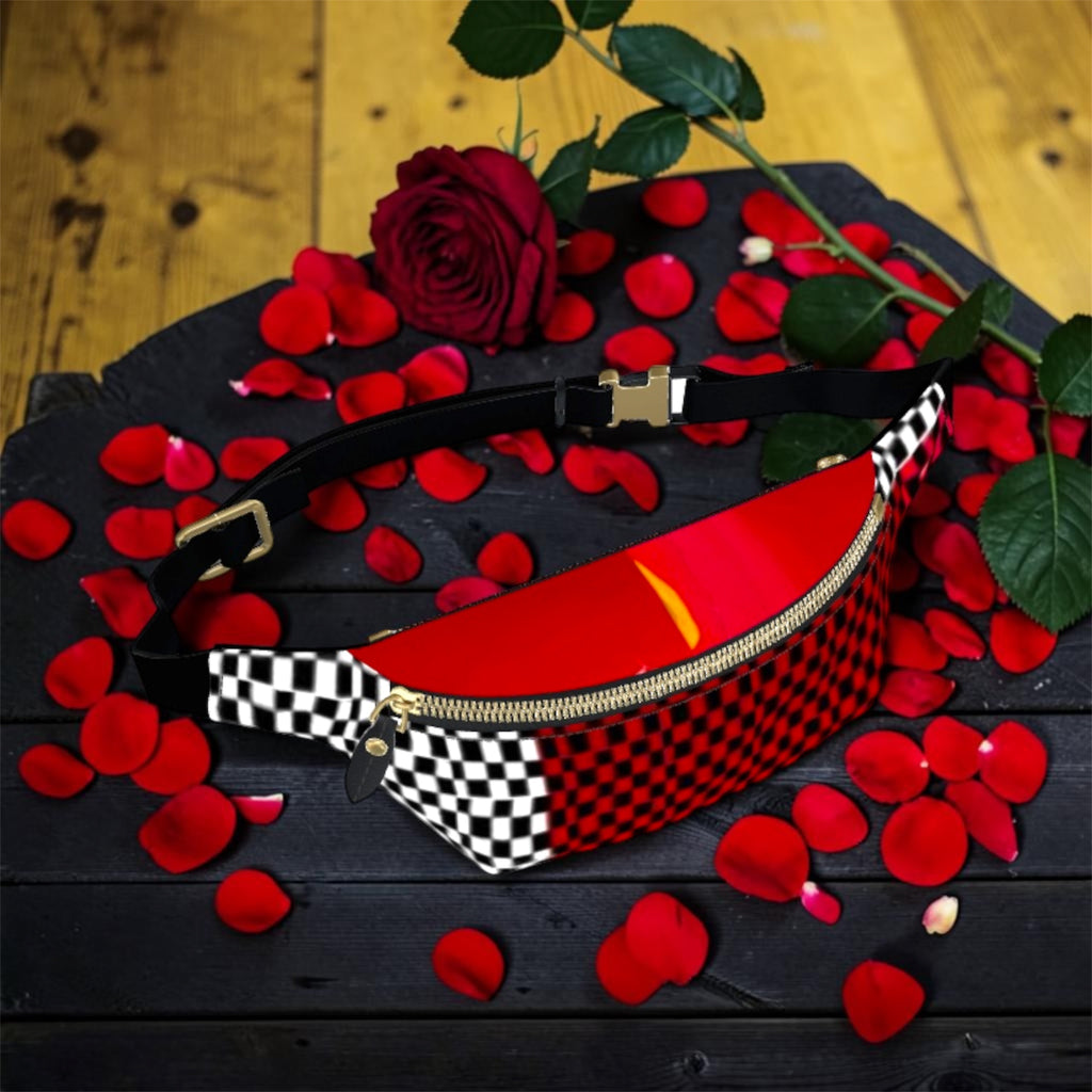 Image 3 (flat lay): Vol IV — The Golden Riot Fanny Pack — flat lay view showing scarlet red & black checkered body with black & white checkered strap, gold zipper and buckle hardware, rose petals scattered on dark wood surface — Golden Expression Art