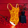 Image 1 — Front view (scarlet red wall, rose petals): Golden Expression Art Vol IV The ICONIC One-Piece — golden yellow all0over ICONIC scarlet red print Lycra one-piece swimsuit, front view, scarlet red wall editorial with rose petals