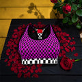 Image 1 (front flat lay, single bra): Vol IV — The Magenta Checkmate Bra Top — magenta and black checkered racerback sports bra with black and white checkered hem band, rose petal editorial backdrop, Stay Golden Edit
