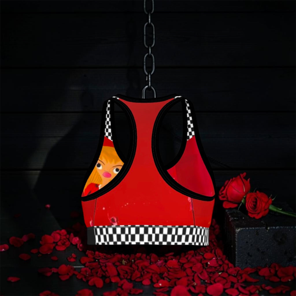 Image 2 (back, hanging on chain, dark backdrop): Vol IV — The Queen Dolly Sports Bra — back view suspended on chain, scarlet red racerback body with Doll Wall art print peeking through, black & white checkered underband, black trim straps, rose petal dark editorial backdrop — Golden Expression Art 