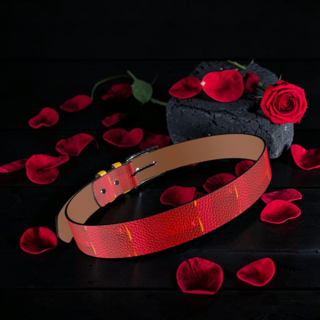 Image 2 — Angled flat lay (rose petals, dark wood): Golden Expression Art Vol IV The Scarlet Flame Belt — angled view showing scarlet red textured leather exterior with flame detail and tan interior lining, surrounded by rose petals