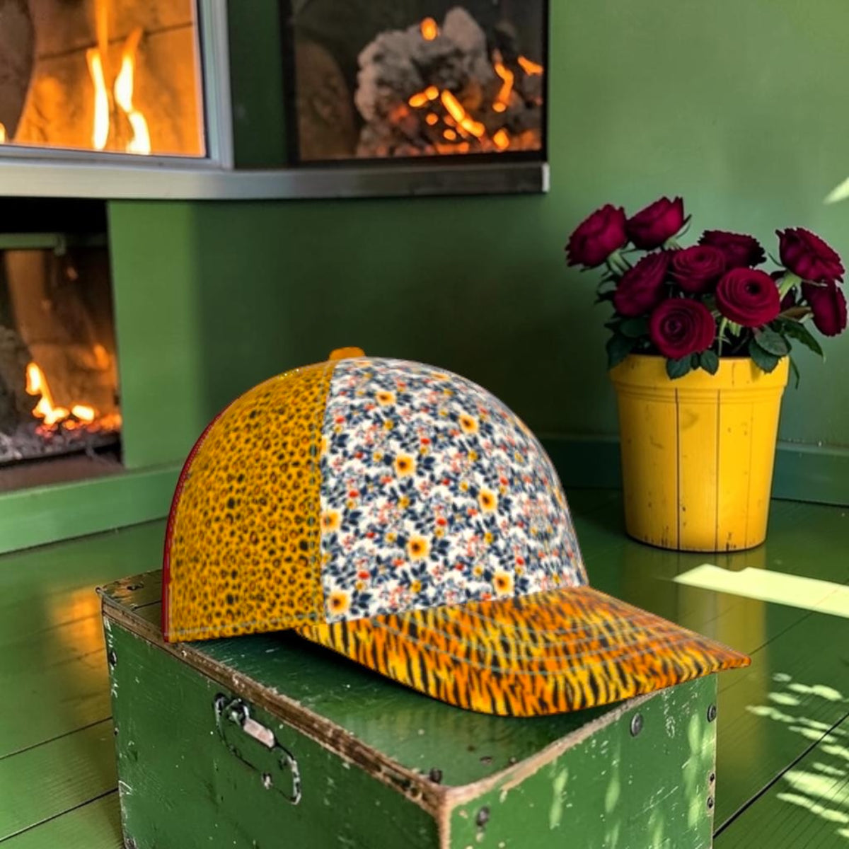 Side view of The Tiger Bloom Baseball Cap showing golden leopard and floral panels with tiger-stripe brim on a green chest in front of a fireplace