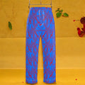 The Unbothered Silk Wide Leg Pant — cerulean blue 100% silk wide leg pant with all-over mirrored scarlet red Karma Bites print, high-waisted elastic waistband, front view on golden yellow backdrop