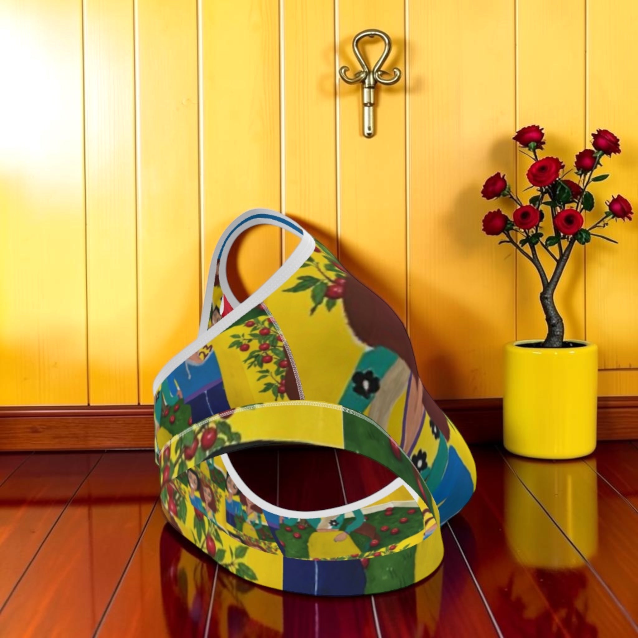 The Eden Empress Sports Bra — bottom band detail, all-over Doll Wall print, yellow wall backdrop