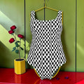 The Check & Gold Bodysuit Swimsuit — front, all-over black and white Checkmate DNA print, scoop neck, slinky matte Lycra