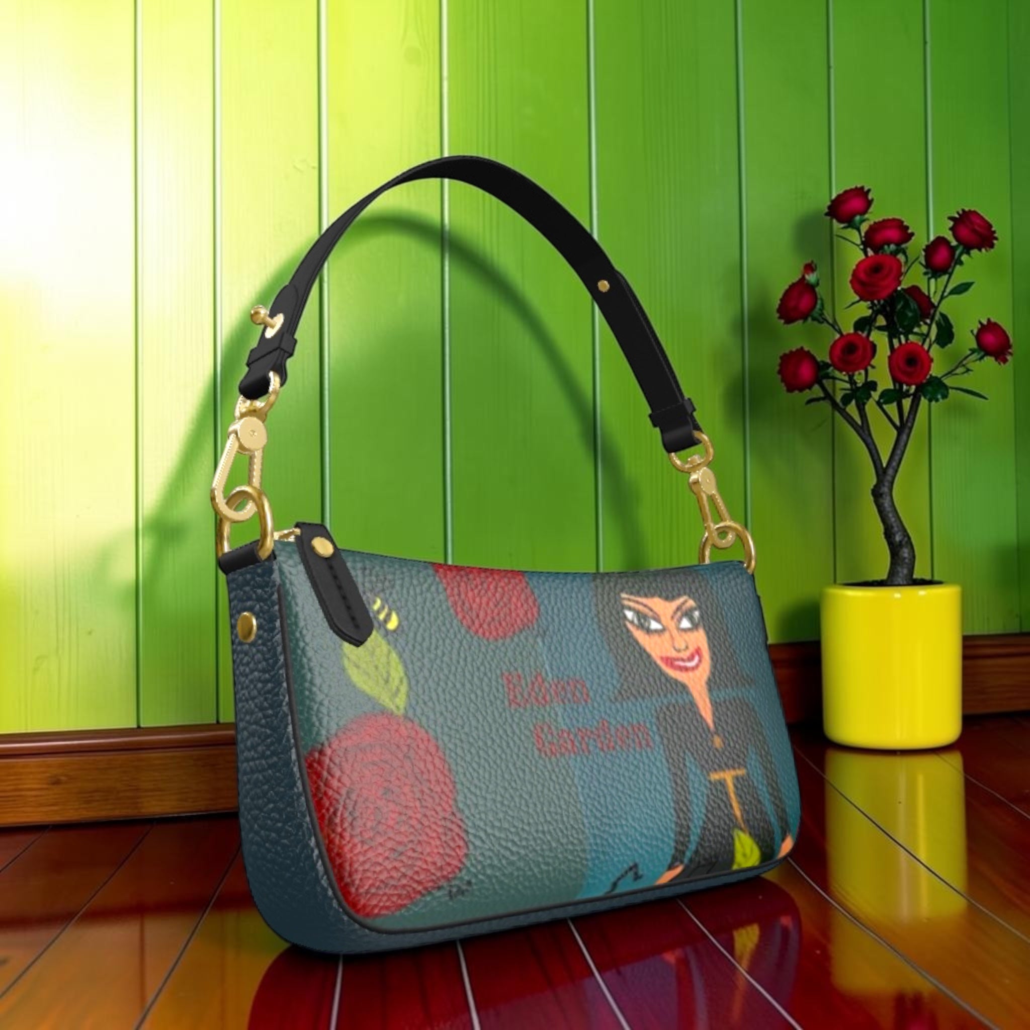 Vol II Queen Goddess Clutch — front view, illustrated goddess print on teal pebbled leather with gold chain strap, green editorial backdrop