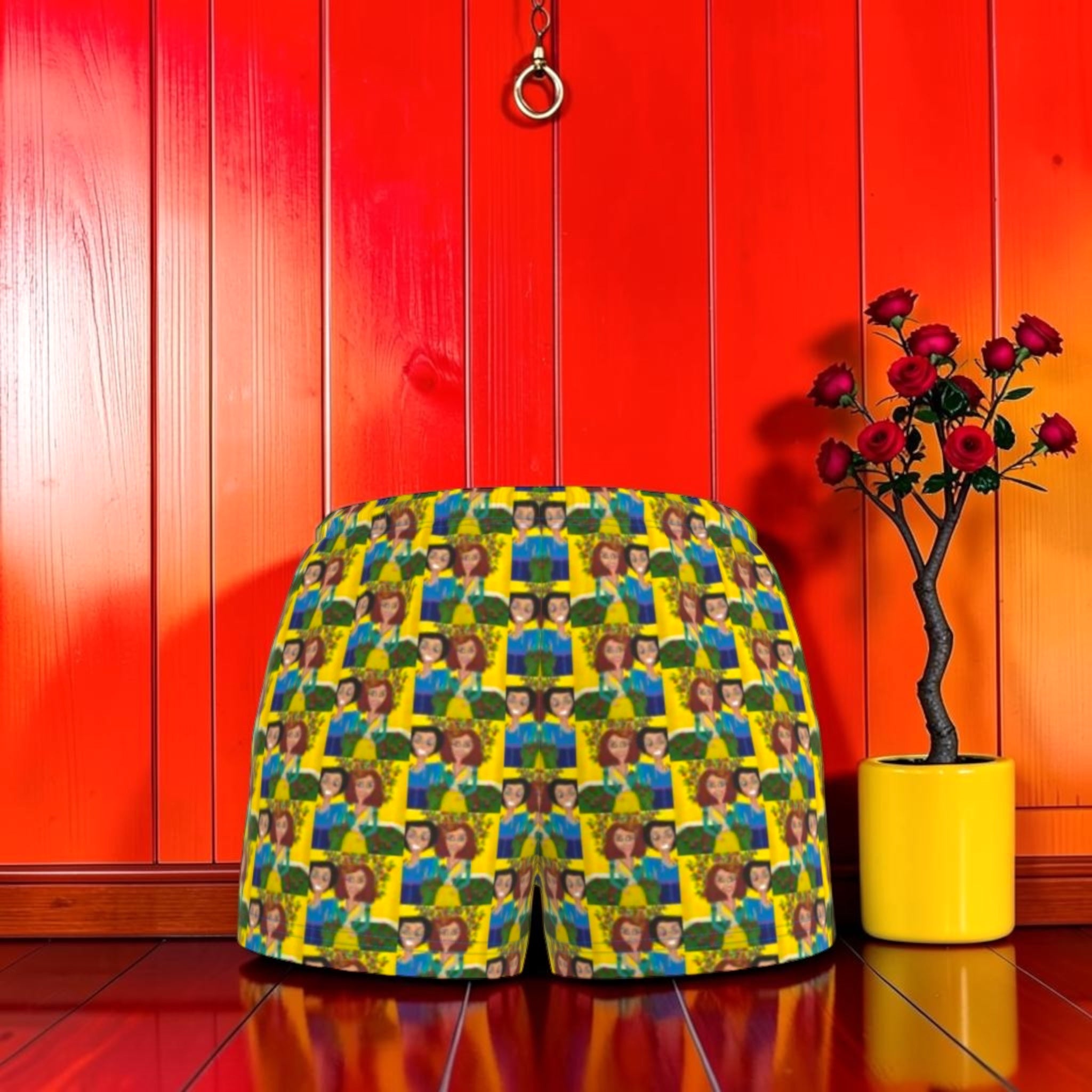 Vol II — The Sacred Garden Short, front view, all-over Eden art print, Doll Wall muse repeating pattern, golden yellow base with blue and green tones, elastic waistband, red editorial backdrop, Golden Expression Art