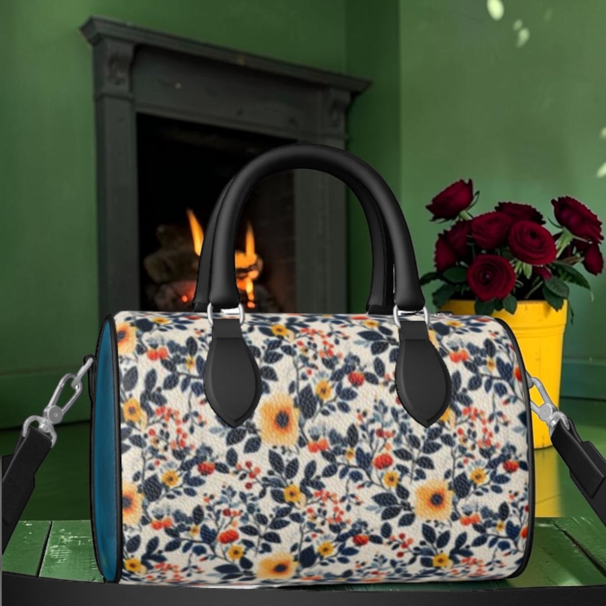The Zebra Bloom Duffle Bag showing the floral print side with black leather top handles and cerulean blue end panel, in front of a fireplace