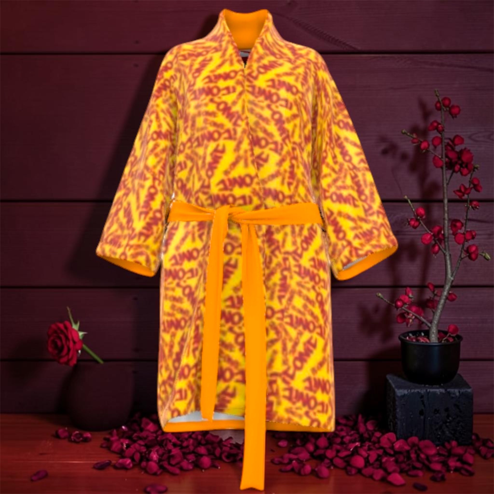 The Decree Kimono Wrap — front view, golden yellow silk with all-over scarlet red ICONIC lettering, self-tie golden sash, rose petal editorial