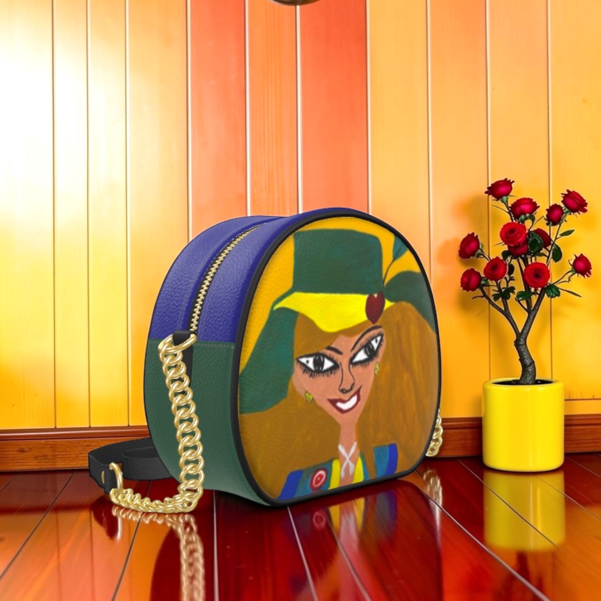 Vol II — The Eden Box Bag, front view, circular structured crossbody, Doll Wall golden lady art print face panel, royal blue top, forest green Nappa leather base, gold chain detail, GEA