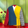 Vol I — The Sovereign velvet blazer wrap front view: slate blue diagonal panel, golden yellow body, scarlet red sleeve, Checkmate DNA black and white checkered sleeve, red collar flash
