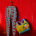 Buttercup Yoga Leggings styled with matching sports bra featuring Doll Wall graphic, hanging against scarlet red paneled wall — Golden Expression Art