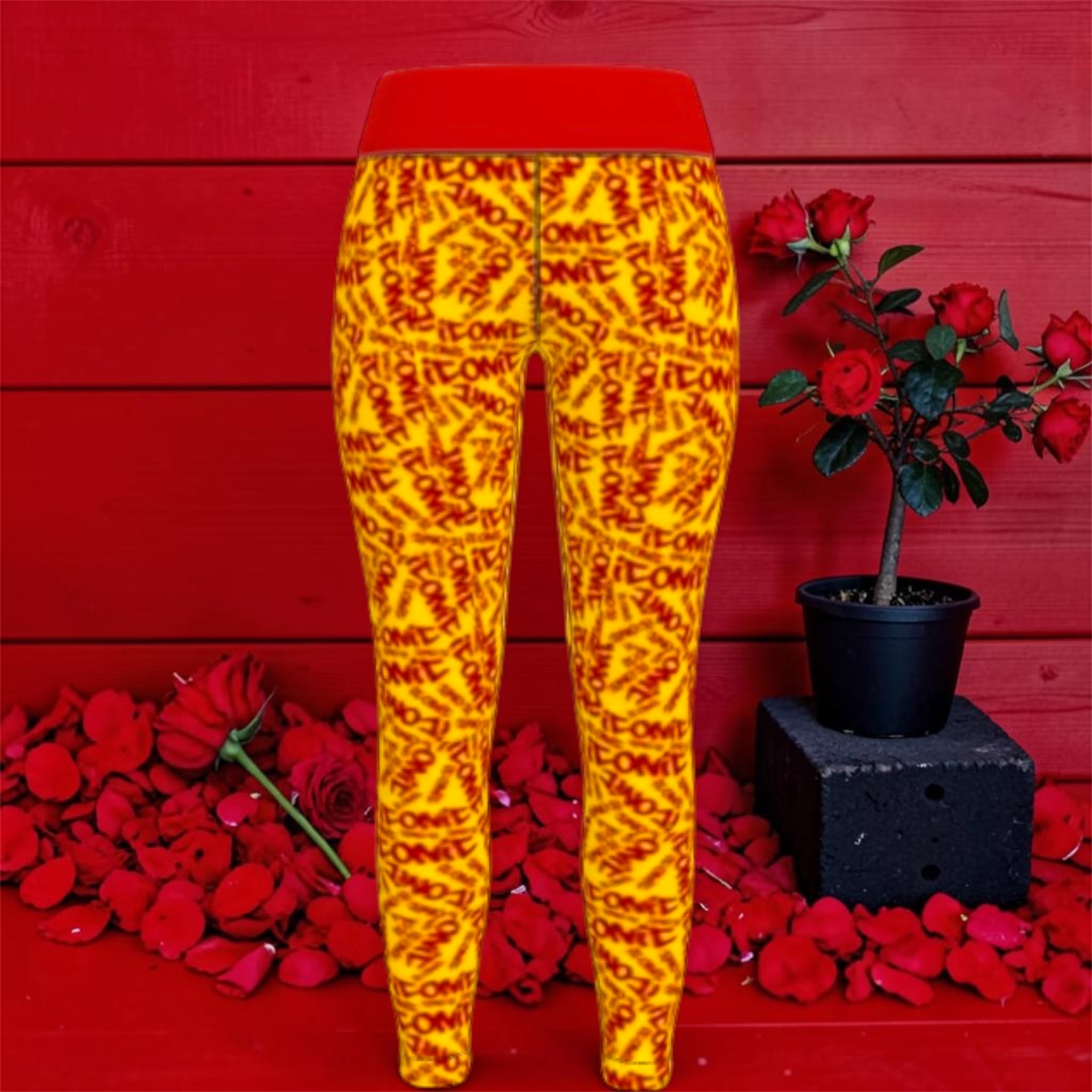 The ICONIC Flex Yoga Pant — front view, golden yellow ICONIC all-over print with scarlet red waistband, rose petal editorial backdrop