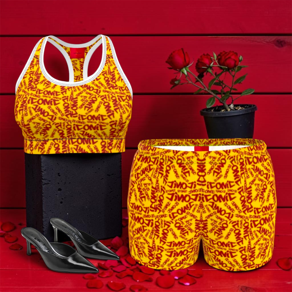 The ICONIC Dream Short — set shot with matching ICONIC sports bra, golden yellow all-over print, white waistband with red detail, styled with black heels and rose petals